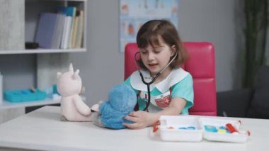 Küçük komik kız doktor olarak steteskop kullanarak tıbbi üniforma giyiyor. Mutlu, sevimli, küçük anaokulu çocuğu, hemşire rolü yapıyor..