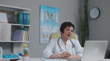 Kadın tıp asistanı beyaz önlük giyiyor, bilgisayardan uzak bir hastayı arıyor. Doktor sanal sohbet bilgisayar uygulaması kullanarak müşteriyle konuşuyor. Teletıp, uzaktan sağlık hizmeti kavramı
