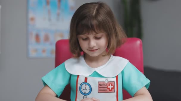 Ritratto di infermiera donna in uniforme medica che guarda la macchina fotografica e sorride al rallentatore. Carino adorabile bambina in età prescolare sorridente in ospedale — Video Stock