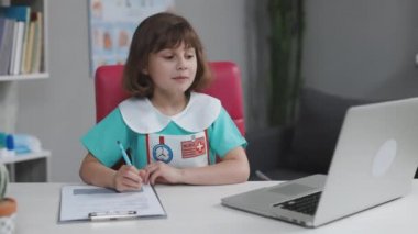 Sevimli küçük kız doktor tıbbi giysiler giyer sosyal medya blogu için kamera kaydına konuşur, video konferansı yapar sanal arkadaşını arar, kanepede oturup sohbet eder.