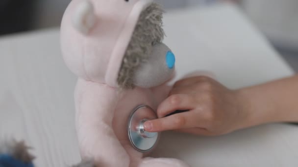 Miúda pré-escolar gira vestindo uniforme médico, ouvindo animais de estimação respirando, pacientes de brinquedo. Criança jogando jogo de hospital fingindo ser médico, veterinário, médico tratar animais sem-teto — Vídeo de Stock