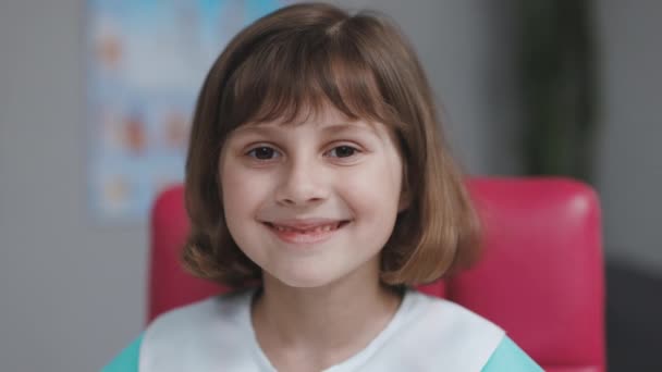 Portrait de sérieux heureux mignon petite fille enfant porter un stéthoscope manteau médical posant en regardant la caméra jouer médecin infirmière concept de profession future. — Video