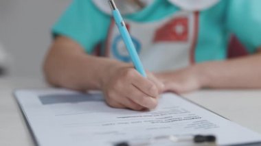 Kırışık küçük kız ellerini tıbbî kayıt defterine bilgi yazarken kapat. Şirin küçük kız tıp önlüğü giyip geleceğin doktorculuğu oynuyor..