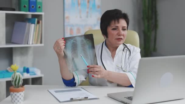 Ärztin im weißen Arztkittel macht Telefonkonferenz am Laptop, berät Fernpatientin online im Videochat, erklärt Behandlung per Webcam-Konzept. — Stockvideo