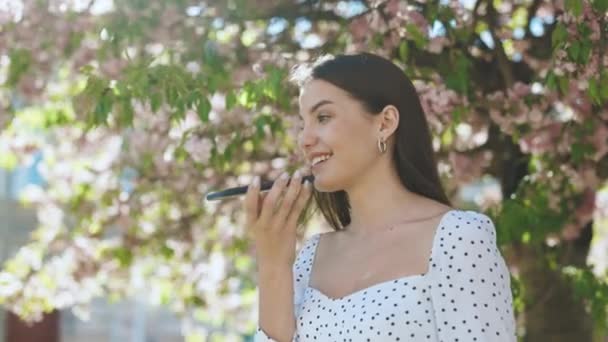 Joyeux jeune fille en utilisant la reconnaissance vocale de téléphone intelligent, dicte pensées, message de composition vocale en plein air parler à l'assistant mobile. Parler bouche dans le haut-parleur d'une jeune femme — Video