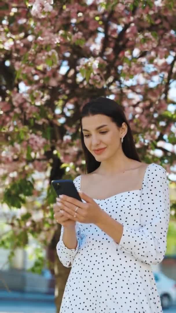 Pionowy portret szczęśliwej kobiety cieszy się sukcesem na telefonie komórkowym. Zbliżenie radosna dziewczyna czyta dobre wieści przez telefon w zwolnionym tempie. Zaskoczona pani świętująca zwycięstwo przez telefon — Wideo stockowe