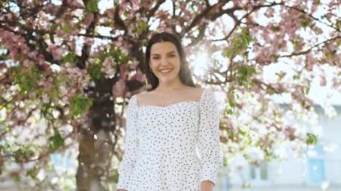 Çekici bir portre... uzun saçlı, gülümseyen bir kadın... gülümseyen bir portre... mutlu bir yaz yüzü... günbatımı... güzel bir bayan. Şehir parkında bahar çiçekleri.