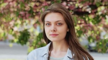 Genç melez Amerikalı kadın portresi. Uzun saçlı Amerikan kadını. Sakura ağaçlarının yanında dikiliyor. İnsan yüzü, ideal doğal makyaj konsepti..
