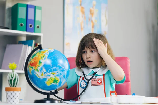 Ecology and global warming concept. Earth Temperature with Thermometer Icon for Global Warming and Climate Change. Little kid girl dressed in a doctors suit measures the temperature of the Earth