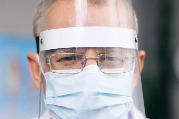 Close up Portrait of male Doctor in Glasses Wearing a Transparent Protective Face Shield, Mask and Overalls in a Hospital Room at the Covid-19. Nurse in medical protective uniform — Stock Photo, Image