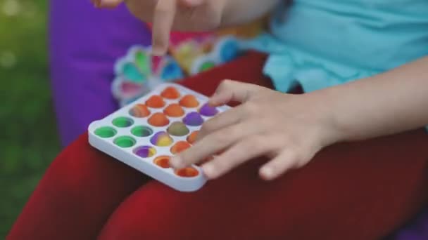 Çocuk elleri gökkuşağı şekerlemesi oyuncağıyla oynar. Dokunmatik ayı şekilli oyuncak yeniden kullanılabilir bir silikon stres giderici oyuncaktır. Stres önleyici terapi oyuncağı patlat ya da basit bir gamze. — Stok video