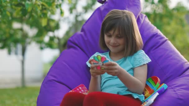 Barnet spelar ett populärt spel med knappar, en anti-stress leksak. Pedagogiska barnlekar. Öppna den. färgglad anti-stress pekskärm. Liten flicka klämmer colorid anti-stress leksak — Stockvideo