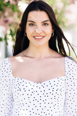 Yaratıcı, canlı makyajlı, dudaklarında pembe ruj ve dışarıda kameraya bakarak poz veren güzel bir kadın. Kapalı portre. Gülümseyen, genç ve çekici bir kadın..