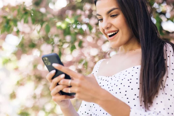 Gros plan joyeuse fille lisant de bonnes nouvelles au téléphone. Dame surprise célébrant la victoire au téléphone. Portrait de femme heureuse profiter du succès sur téléphone mobile — Photo