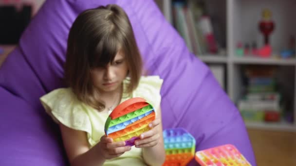 Menina apertando colorido brinquedo anti-stress. A criança está jogando um jogo popular com botões, um brinquedo anti-stress. Jogos educativos infantis. Abre. tela sensível ao toque anti-stress colorida — Vídeo de Stock