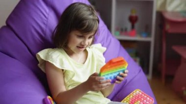 Çocuk düğmelerle popüler bir oyun oynuyor, stres önleyici bir oyuncak. Eğitici çocuklar oyunlar oynar. Patlat. Renkli stres önleyici dokunmatik ekran. Renkli anti-stres oyuncağı sıkan küçük kız.