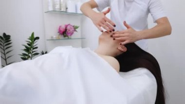 Beyaz kadın estetik bir salonda yüz masajı yaptırıyor. Güzellik salonunda yüz masajı. Spa yüz masajı. Vücut bakımı, cilt bakımı, sağlık, refah, güzellik tedavi konsepti