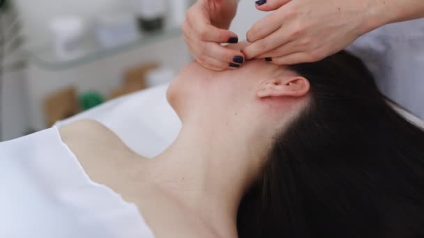 Genç bir kızın yüz masajı yaptırdığı ve lüks bir sağlık merkezinde mükemmel cilt için spa tedavisi gördüğü yakın plan. — Stok video
