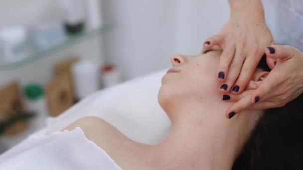 Kozmetik uzmanı kızların yüzüne dokunuyor. Profesyonel kozmetik yüz masajıyla yüz temizleme. Kadın kaplıcada kozmetik tedavisi görüyor. — Stok video