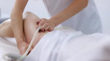 Bacak anti-selülit prosedürleri. Kadın sağlığı ve güzelliği. Donanım anti-selülit masajı. RF kaldırma prosedürü. Güzellik uzmanı cihazı müşterinin bacağı boyunca yönlendirir.