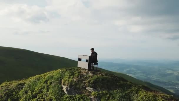 Flygfoto av pianisten spelar i vackra flygeln i bergen. Man två händer spelar mild klassisk musik på en flygel på naturen. Professionell pianist. Man rör fingrarna på tangenterna — Stockvideo