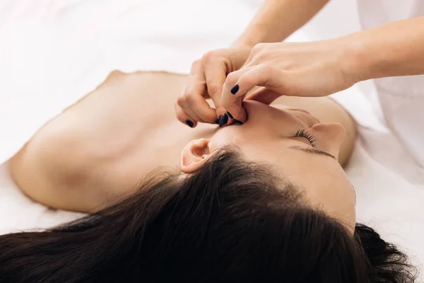 Cosmetoloog raakt meisjes gezicht. Gezichtsreiniging met professionele cosmetische gezichtsmassage. Vrouw heeft cosmetische behandeling in spa salon — Stockfoto