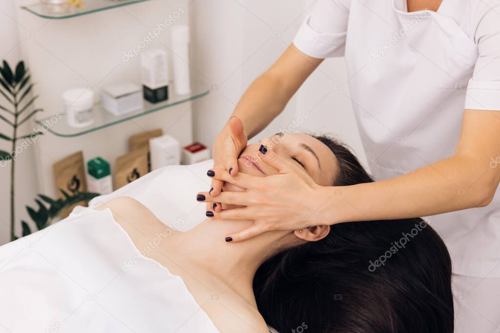 Face Massage in beauty spa salon. Caucasian woman receiving a facial massage at an aesthetic salon. Spa facial Massage. Body care, skin care, wellness, wellbeing, beauty treatment concept