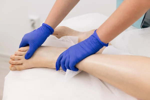 Médico em luvas examinando joelho doloroso de paciente feminino trauma na perna. Conceito de seguro médico de saúde. Trabalhadora fisioterapeuta mulher auxiliando a recuperação do exercício físico médico após lesões — Fotografia de Stock