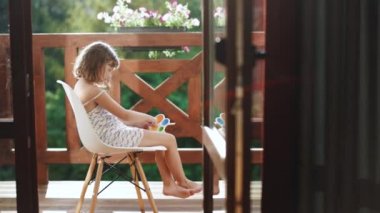 Modern popit, basit gamzeli snapperz oyuncağı olan küçük bir kız. Renkli ve parlak bir oyuncak. Basit bir gamze. Çocuk renkli bir anti-stres oyuncağıyla sandalyede oturuyor. Basit bir gamzesi var.