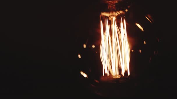 Gloeilamp Warm geel licht over donkerzwarte achtergrond. Helder gloeiende Edison Tungsten lamp. Retro vintage vorm. Creatief idee concept. Close-up van een wolfraam gloeilamp inschakelen — Stockvideo
