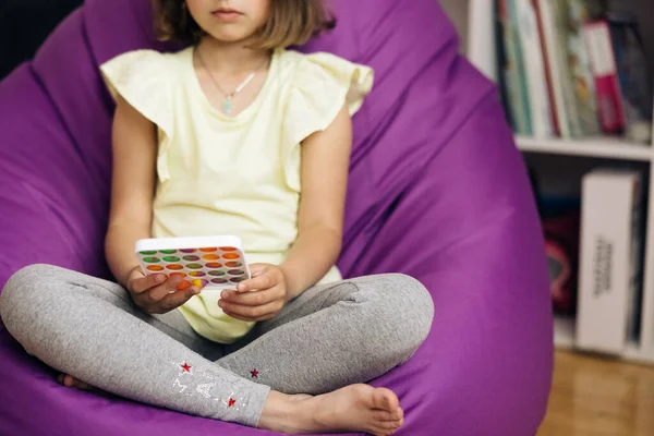 Little girl with a modern popit simple dimple snapperz toy. Colorful and bright toy. Simple dimple. Child is sitting on chair with colorful trendy antistress sensory toy pop it simple dimple snapperz