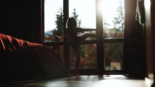 Silhouette kleines Mädchen talentierte Tänzerin macht Ballett-Posen Dehnübungen zu Hause. Lebensstil in der Wohnung, Turnen und Gewichte auf dem Balkon. Professionelle Ballerina tanzt im Scheinwerferlicht — Stockvideo