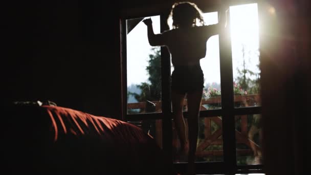 面白い愛らしい幸せな子供の女の子は、午前中に寝室で楽しいダンスをしてジャンプします。Silhouette幸せな気楽な若いです女の子ダンス一人で現代的なリビングルームで大きな窓 — ストック動画