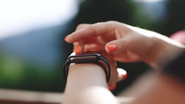 Un reloj inteligente. Mujer joven usando reloj inteligente al aire libre. Primer plano de la pantalla táctil táctil femenina en reloj entrar aplicación de reloj. Mujer de negocios desplazándose en la pantalla smartwatch — Vídeo de stock