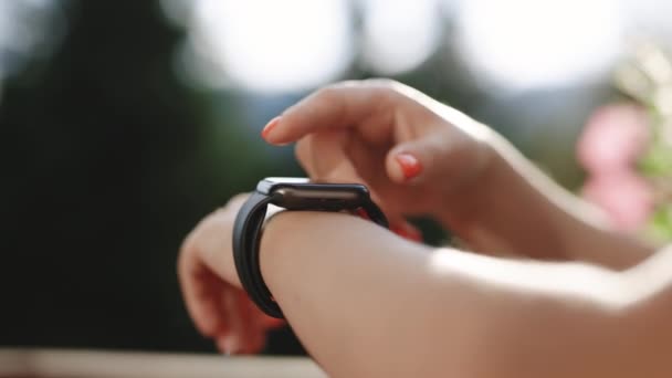 Espertinho. Relógio inteligente em uma mão de mulheres ao ar livre. Mão de meninas tocando um smartwatch. Exibição de rolagem no relógio inteligente. Conceito de entretenimento e tecnologia. — Vídeo de Stock