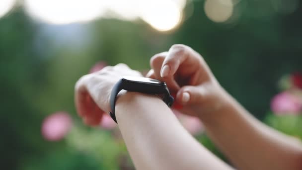 Reloj inteligente en muñeca femenina. Chica comprobar el pulso en pulsera de fitness. Un reloj inteligente. Mujer joven usando reloj inteligente. Tocar la pantalla táctil femenina en reloj entrar aplicación reloj — Vídeo de stock