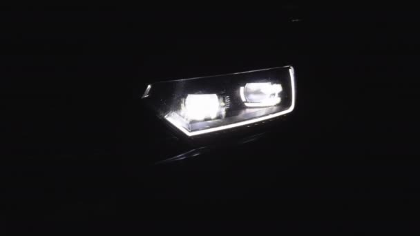 밤에 자동차 LED 헤드라이트를 교체하는 것. 새로운 현대 자동차 헤드램프. 자동차 앞에 는 불빛 이 배경에 흐릿하게 비치고 있다. 번쩍 이는 자동차 헤드라이트 — 비디오