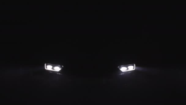 Nahaufnahme des Scheinwerfers beim Einschalten von LED-Scheinwerfern in der Nacht. Neue moderne Autoscheinwerfer. LED-Licht vor dem Auto mit verschwommenem Hintergrund — Stockvideo