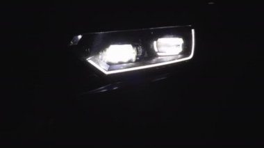 Farları düzgün yanıp sönen bir araba. Yaklaş. Araba Önü Led Light. Araba farları yanıp sönüyor. Gece araba LED farlarının değişmesi. Yeni modern araba farları