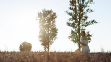 Provence, Fransa 'da güzel bir kızın arkasında. Aromaterapi. Beyaz elbiseli mutlu genç kadın lavanta tarlasında koşuyor. Doğa Arkaplanı. Yavaş Hareket 100 Fps