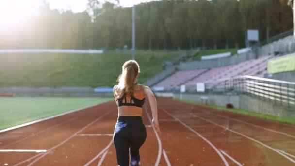 Fiatal sportoló nő gyorsan fut a pályán a reggeli fény, edzés kemény, felkészülés a verseny verseny vagy a maraton. Fit Girl fekete sportruházat kocogás egy futó pályán — Stock videók