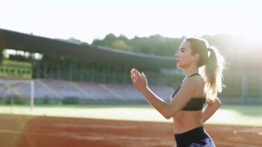 Aktif fitness kadın koşucusu açık havada güneşli pistte koşuyor. Bayan sporcu sabah ışığında koşu antrenmanında. Koşucu aktivitesi. Sporcu kadın. Kardiyo egzersizleri. Egzersiz konsepti