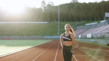 Siyahi spor kıyafetleriyle koşan beyaz bir kadının spor stadyumunda spor yaparken görüntüsü. Yetişkin bayan atlet koşu, maratondan önce antrenman. Sağlığa. Sporcu Kadın.