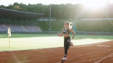 Beyaz kadın spor kıyafetleriyle koşuyor stadyumun spor pistinde kardiyo çalışması yapıyor. Yetişkin bayan atlet koşu, maratondan önce antrenman. Sağlığa. Sporcu Kadın.
