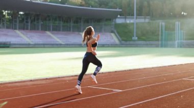 Atletizm pistinde antrenman yapan bayan koşucu. Yaz sabahı vakti stadyumda koşan atletik bir kadın. Eğitim sırasında hipodromda koşan formda bir kadın. Sporcu Kadın