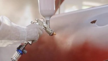 Otomobil boyacısı özel bölmede arabanın kapısına kırmızı boya sıkıyor, yavaş çekimde. Araba servisi atölyesinde araç parçaları boyuyorum. Araba üretim fabrikası