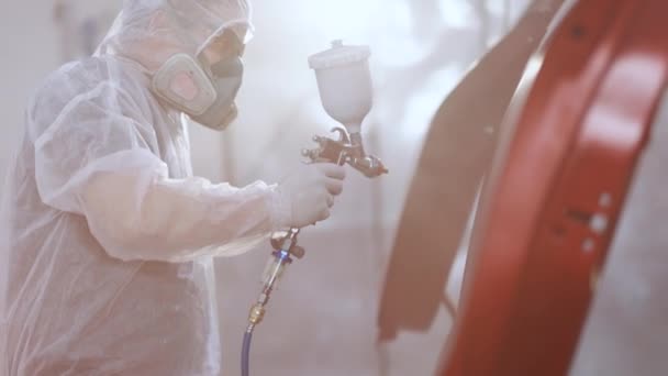 Técnico masculino é ar-pintura carros porta. Processo de pintura spray industrial. Auto pintor pulverizando tinta vermelha na porta do carro em cabine especial. Pintura de peças de veículos na oficina de serviço de carro — Vídeo de Stock