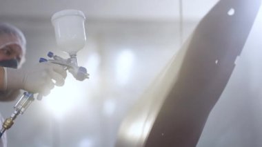 Erkek teknisyen hava boyalı araba kapısı. Endüstriyel sprey boya işlemi. Oto boyacısı özel kabinde arabanın kapısına kırmızı boya sıkıyor. Araç parçaları araba servisi atölyesinde boyanıyor