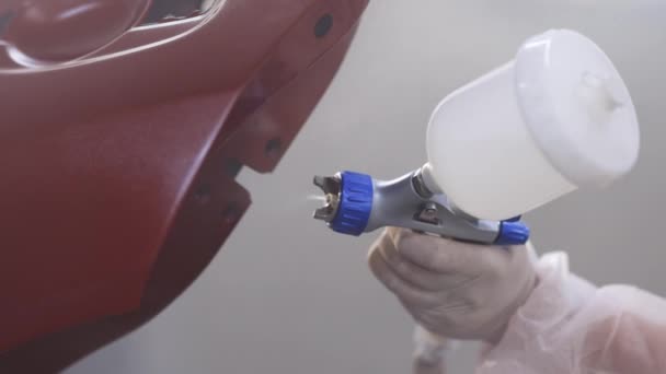 Pintor pinta o carro vermelho na garagem. pintura de carro com pistola de pulverização profissional. Mestre está pintando parte do automóvel no serviço de carro — Vídeo de Stock