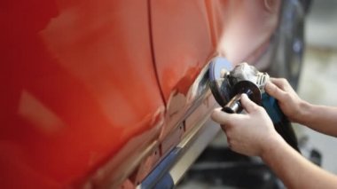 Araba tamircisi. Araba göçüğü temizleme teknikleri, araba tamircisi tamircinin araba gövdesini sökmesi. Garaj tamircisi işe başlamadan önce Öğütücüyle boyayı kaldırıyor..